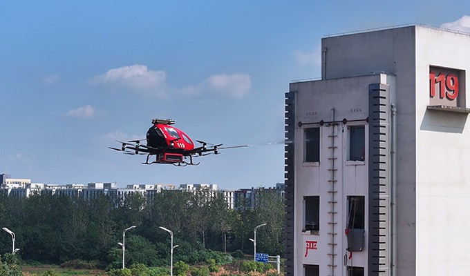 EHang EH216-F autonomous firefighting eVTOL deploying fire suppression on a high-rise building — pilotless emergency response already operational in China
